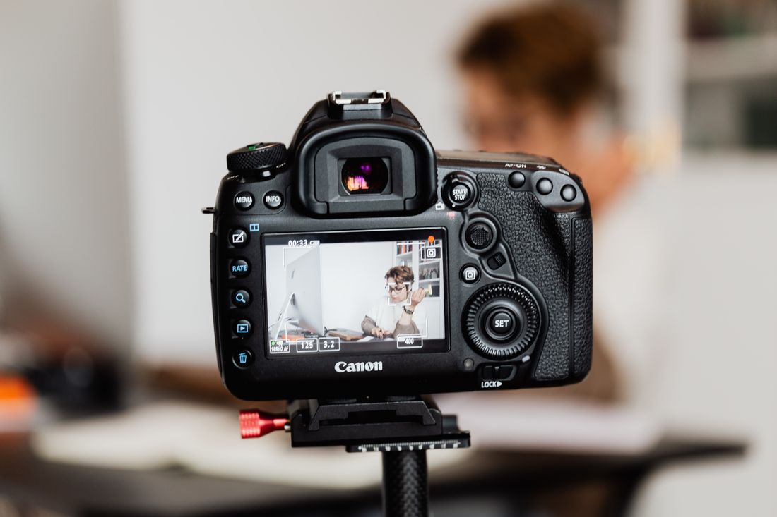 A camera on a tripod set up in a modern office workspace for a recurring video recording.