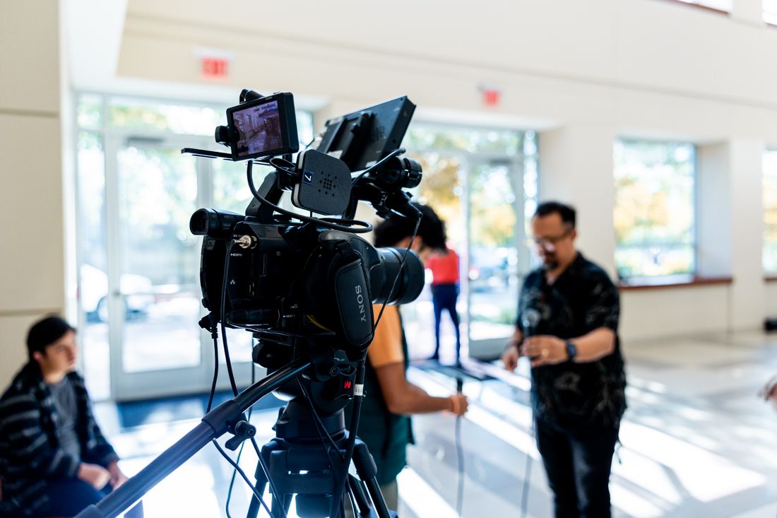 Close-up of a professional video camera mounted on a tripod, set up for a repeatable recording format.