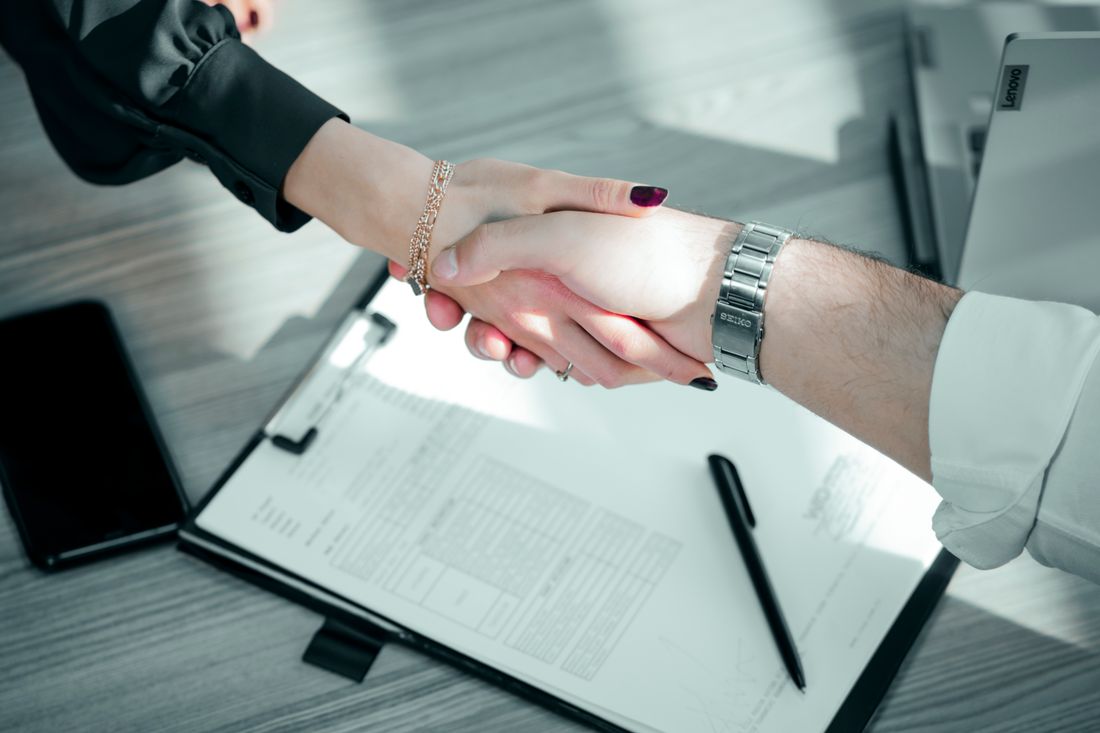 Close-up of a professional handshake over a contract on a desk