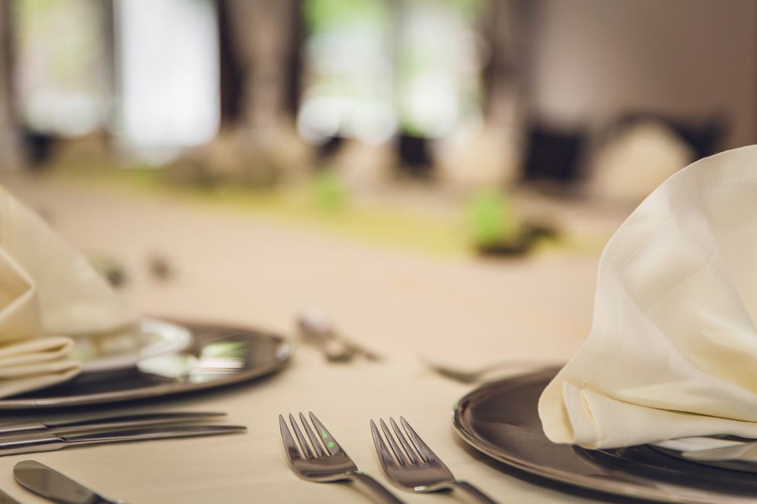 A refined dining table setting with neatly folded napkins and cutlery on elegant plates