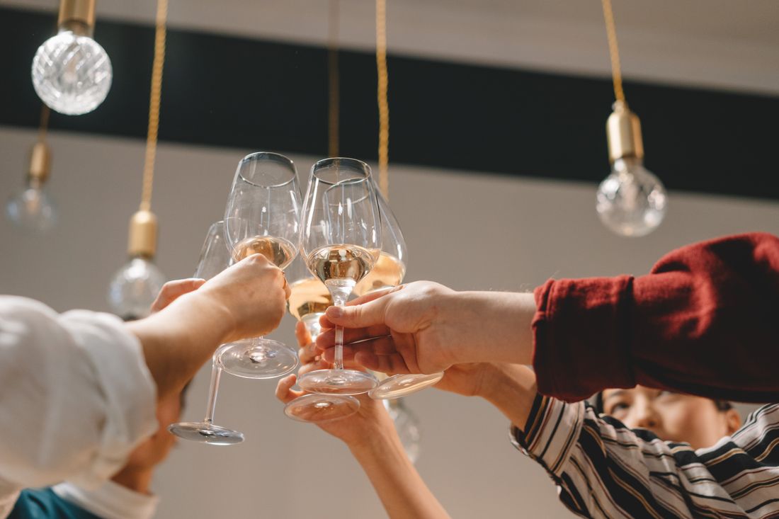 Close-up of hands toasting glasses of sparkling wine at an indoor celebration.