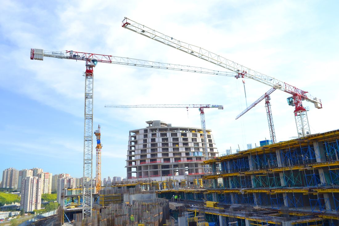 Urban construction site with multiple tower cranes against a city skyline