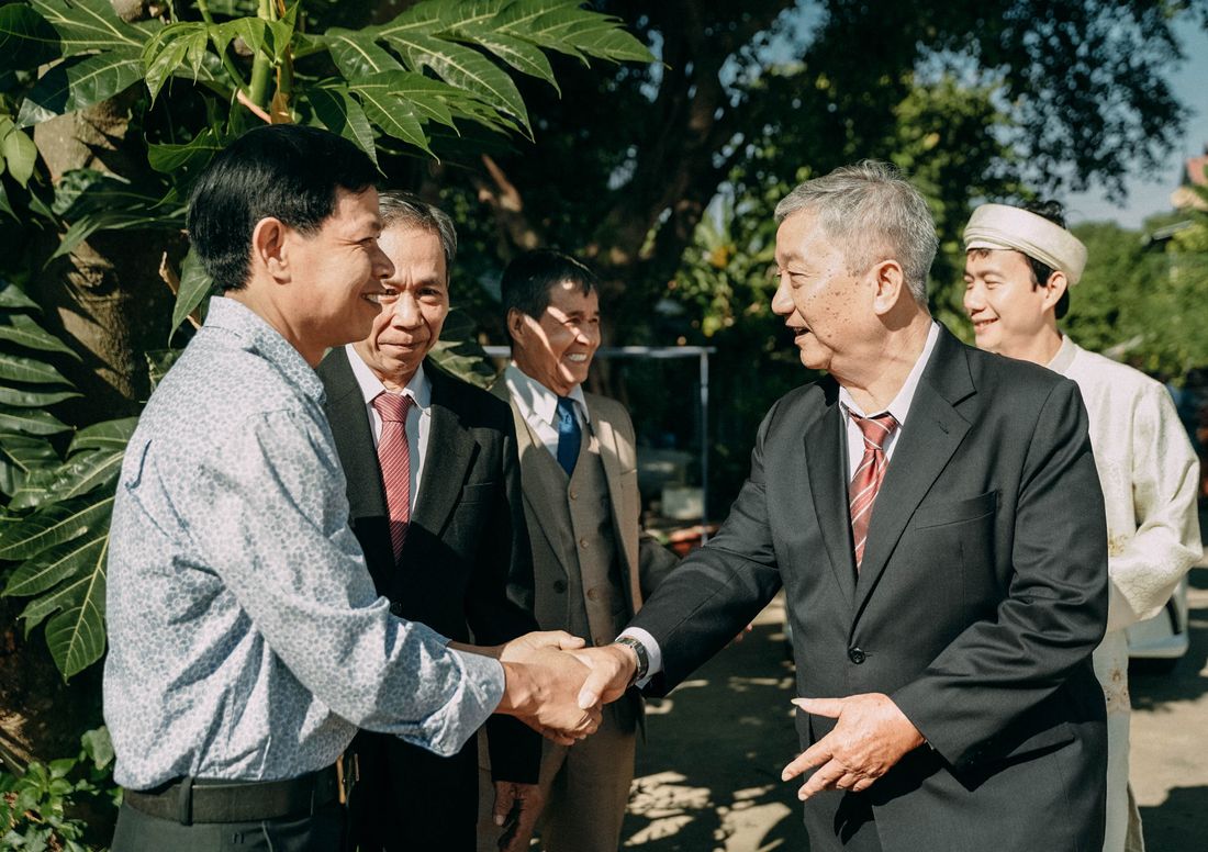 Group of people in formal attire shaking hands outdoors