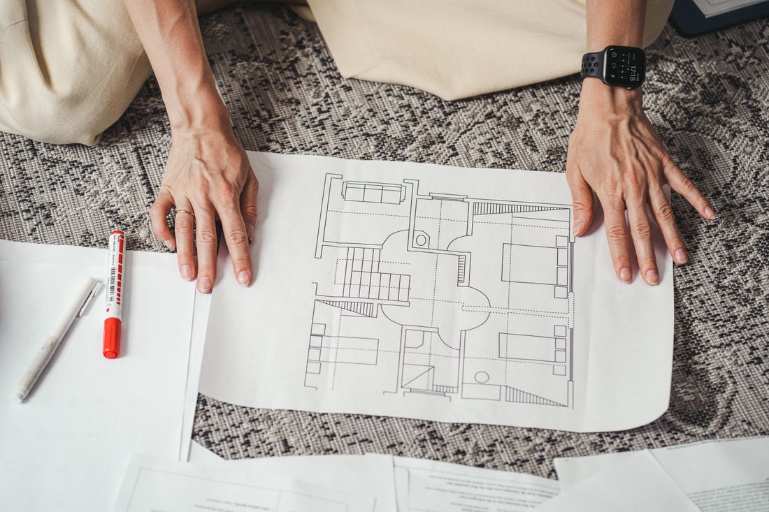 A close-up overhead view of hands spreading out a printed floor plan document.