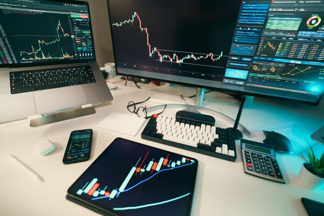 Modern trading desk with multiple screens displaying financial charts and graphs