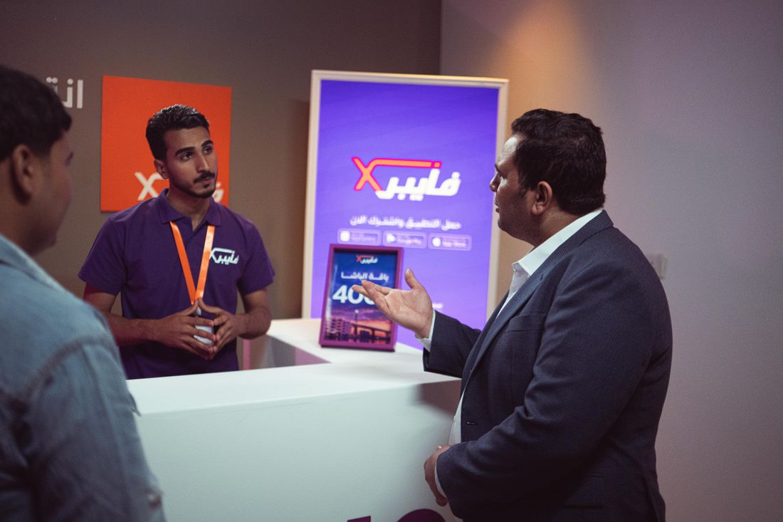 Staff member engaging with a visitor at a technology exhibit booth