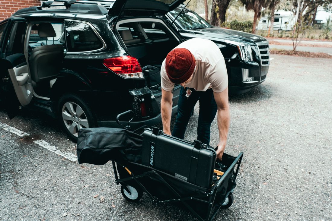 Production gear case being wheeled out of an SUV trunk in a parking lot, illustrating equipment transport for an outside-Manhattan shoot.