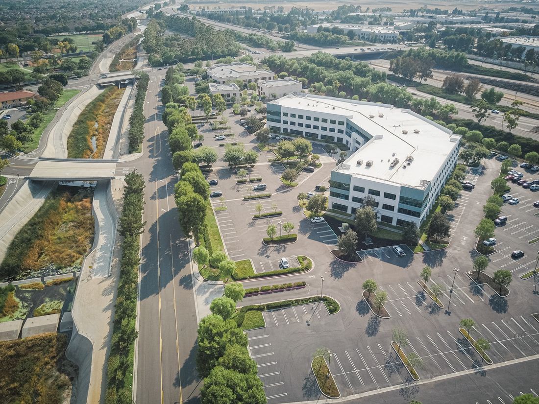 Aerial view of a suburban office building surrounded by a large empty parking lot, typical of a Westchester or Long Island shoot location.