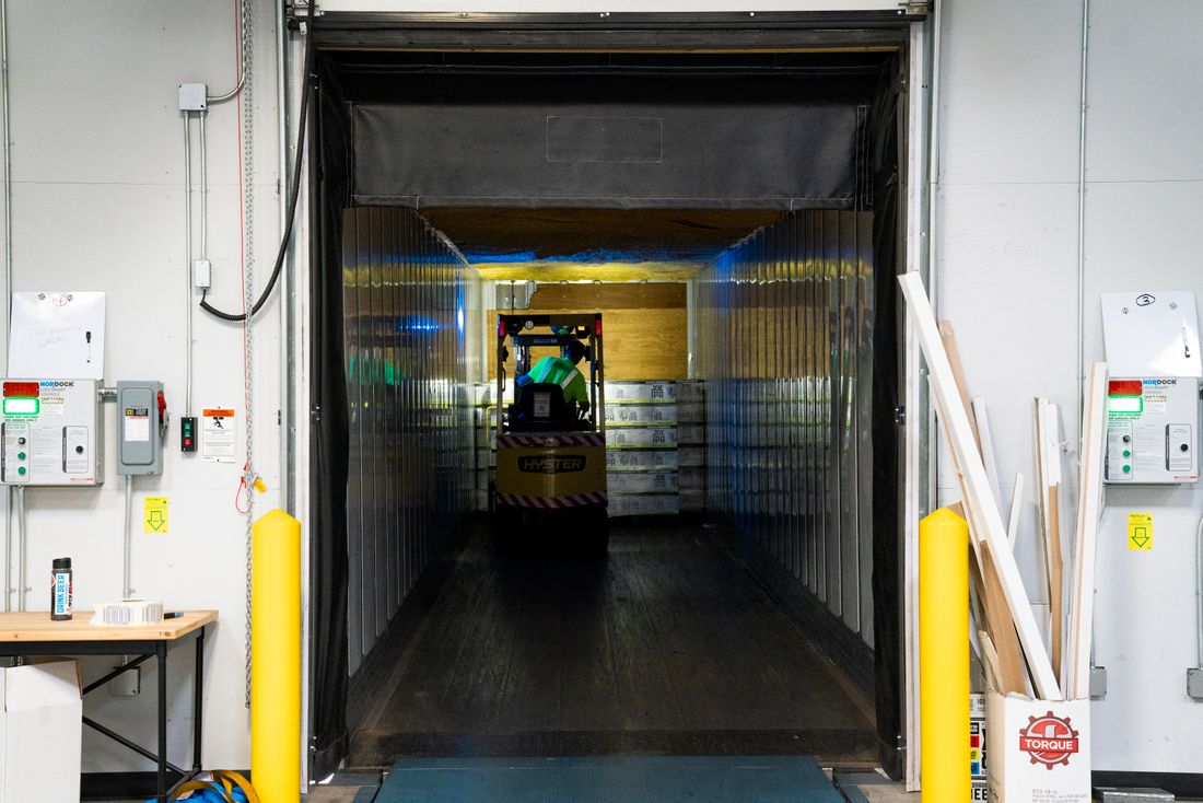 Forklift moving pallets along an industrial loading dock pathway