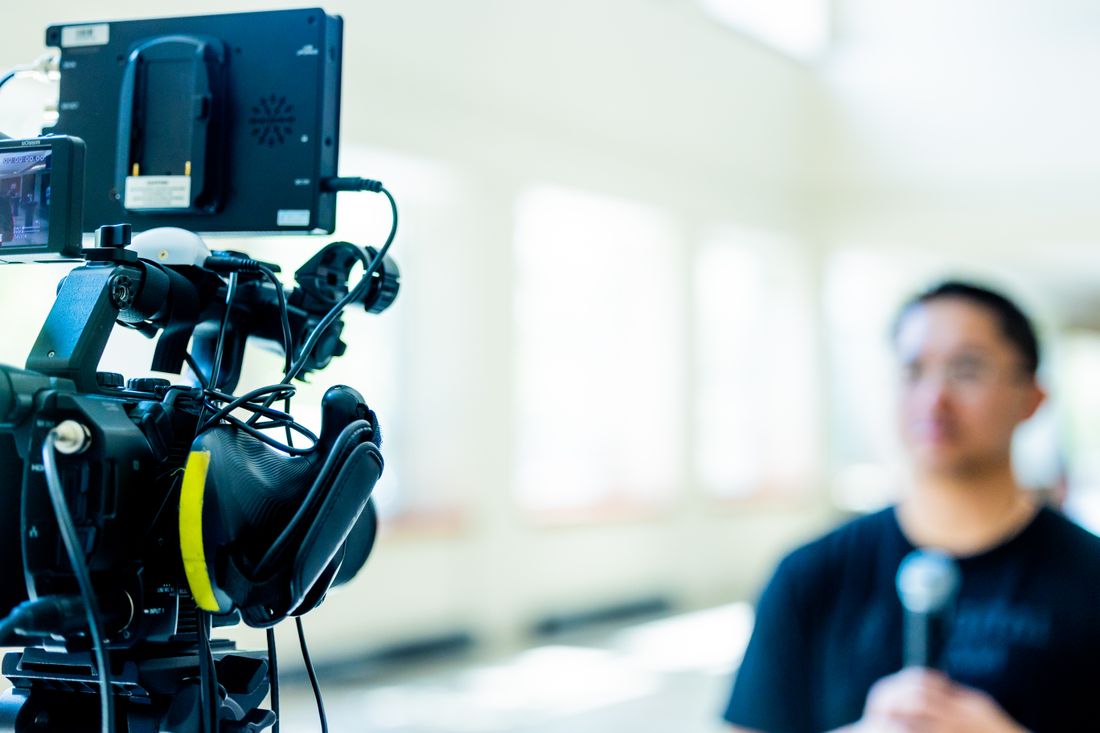 Video camera with monitor pointed at a presenter during a filmed interview setup