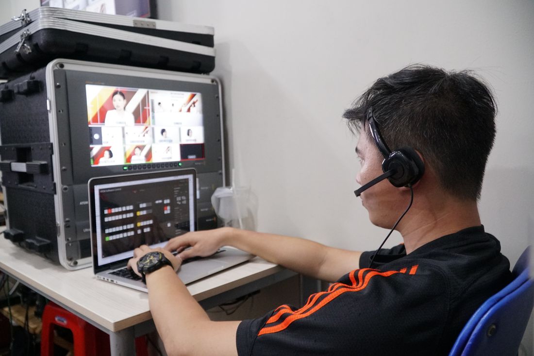 Technician wearing a headset monitoring a video call grid and switcher on a laptop during a live production