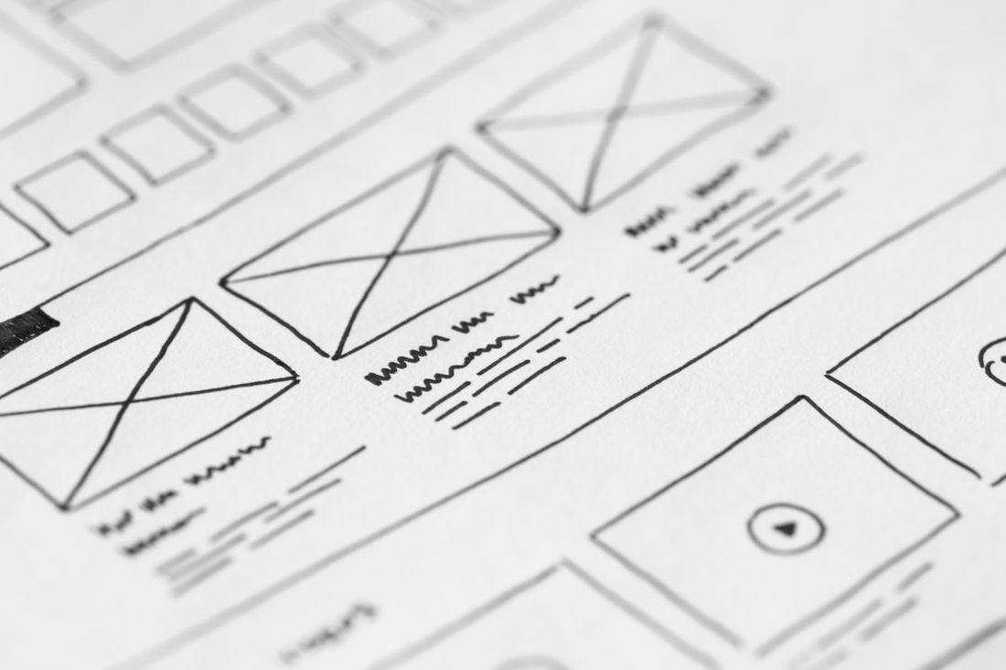 A hand-drawn wireframe sketch on paper, laying out image and content blocks for a website redesign.