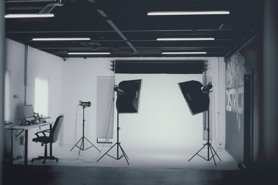 A black-and-white photography studio with two separate softbox lighting setups built on either side of a white backdrop.
