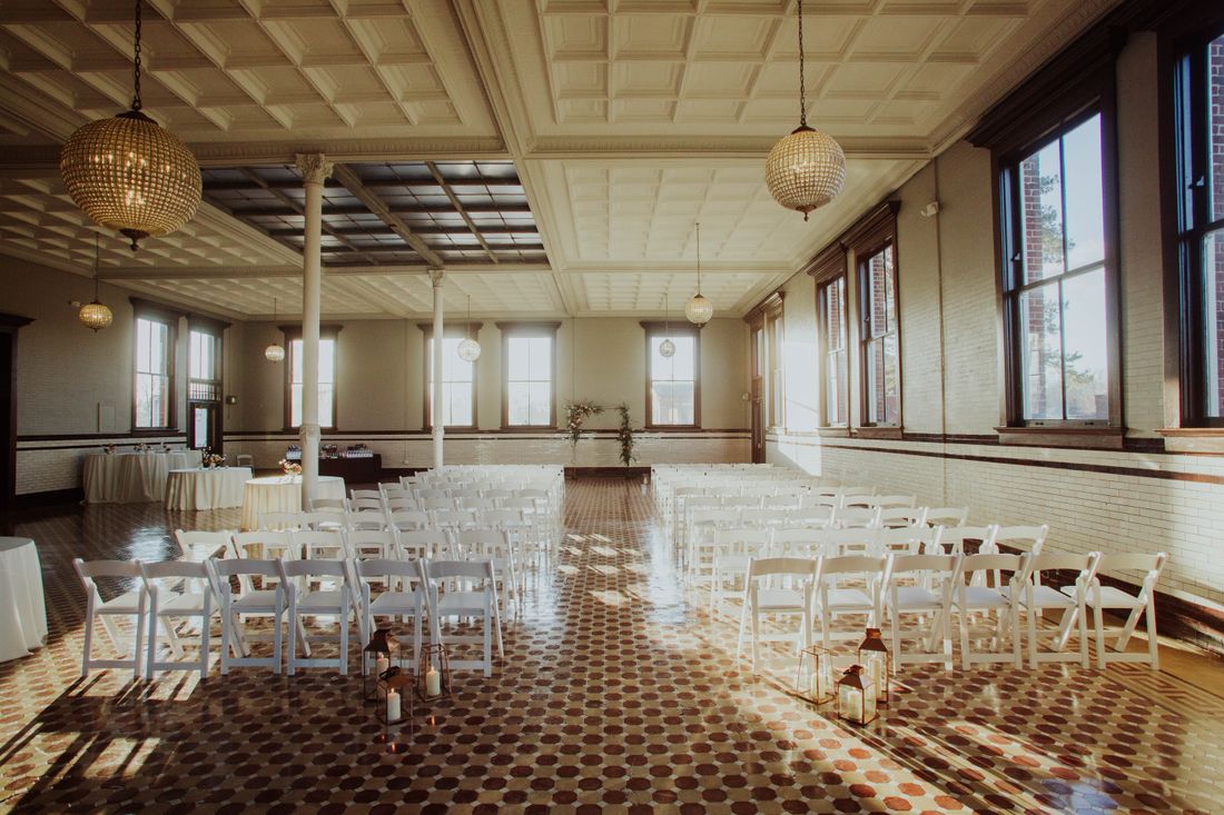 Empty elegant event space with rows of white folding chairs set up before guests arrive, warm ambient lighting
